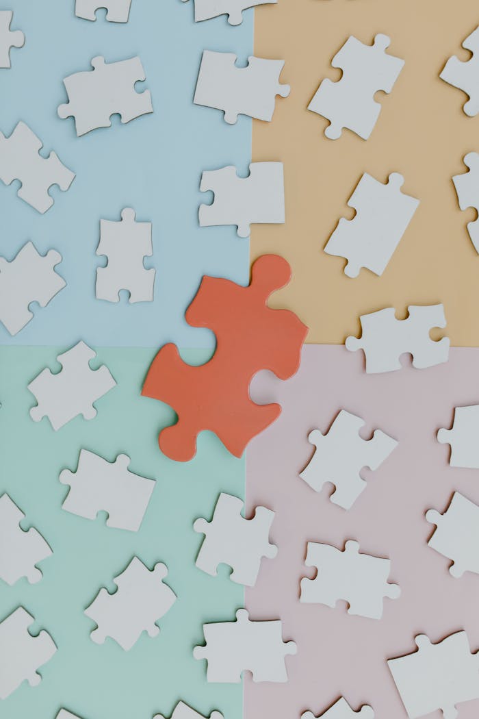 An arrangement of puzzle pieces on a pastel-colored background featuring a standout red piece.